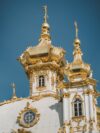 A large white and gold building with a clock on it's side