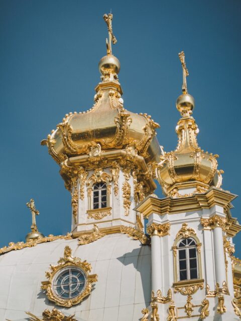 A large white and gold building with a clock on it's side