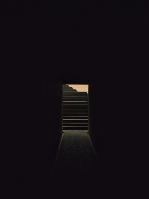 A dark tunnel with a stairway leading to the sky