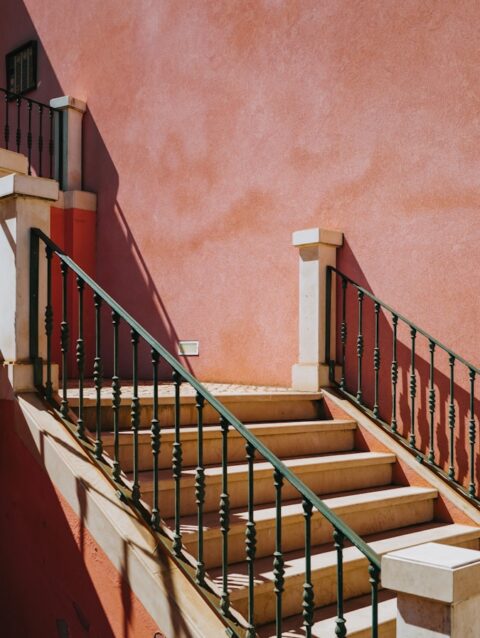 A red building with a green railing and a red wall