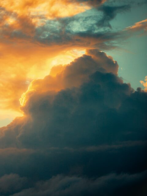 A plane flying through a cloudy sky at sunset