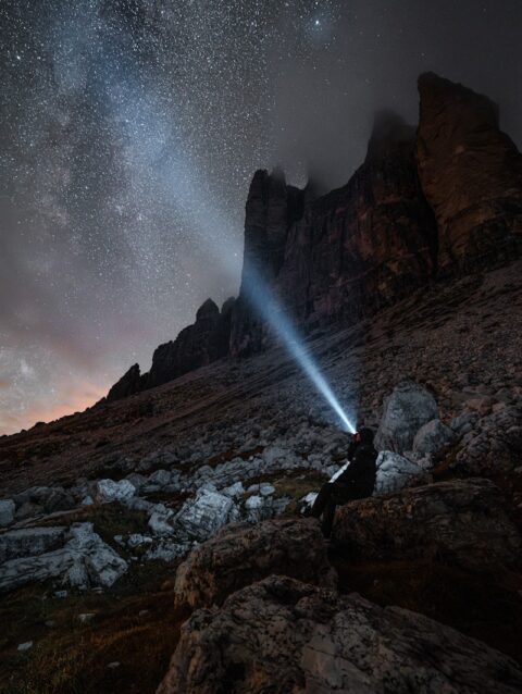 A person standing on top of a mountain under a night sky