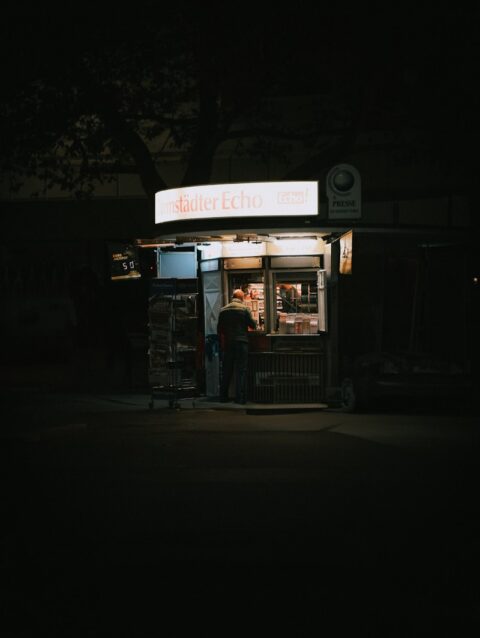 A man standing in front of a store at night