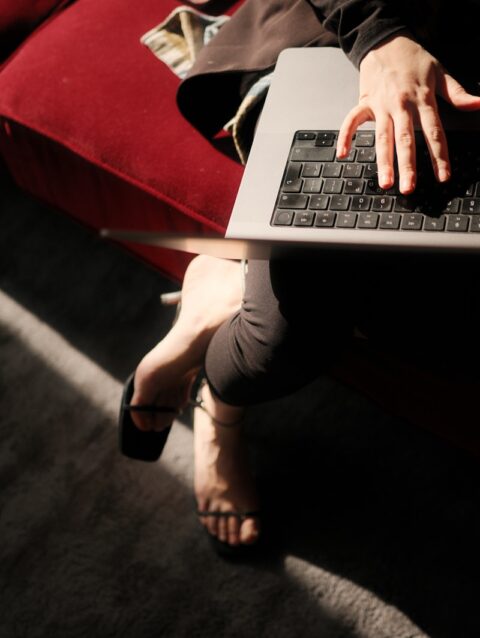 A woman sitting on a couch using a laptop computer