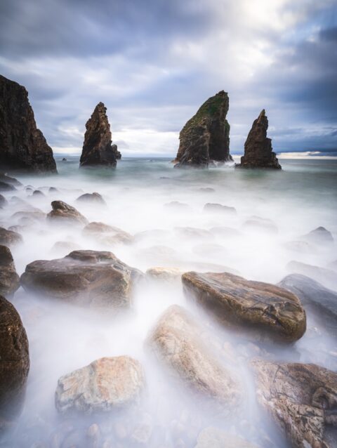 A long exposure photo of rocks in the ocean