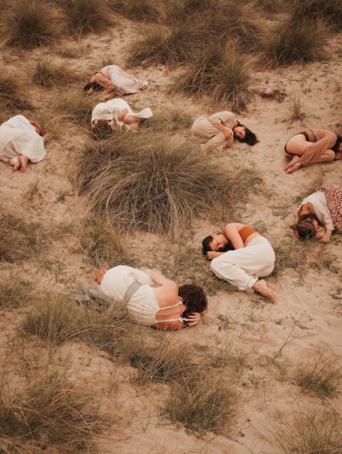 A group of people laying on top of a sandy beach