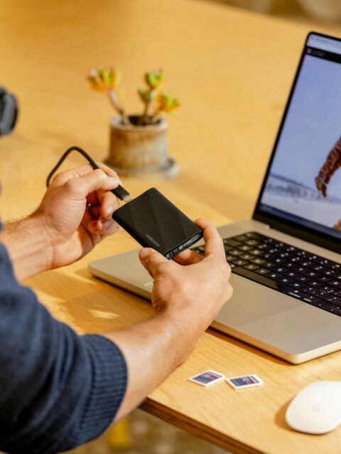 A man sitting at a table with a laptop and cell phone