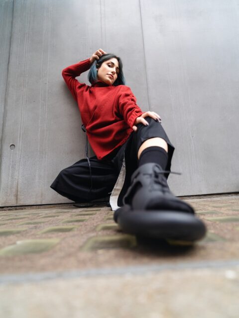 A woman in a red shirt and black pants sitting on the ground