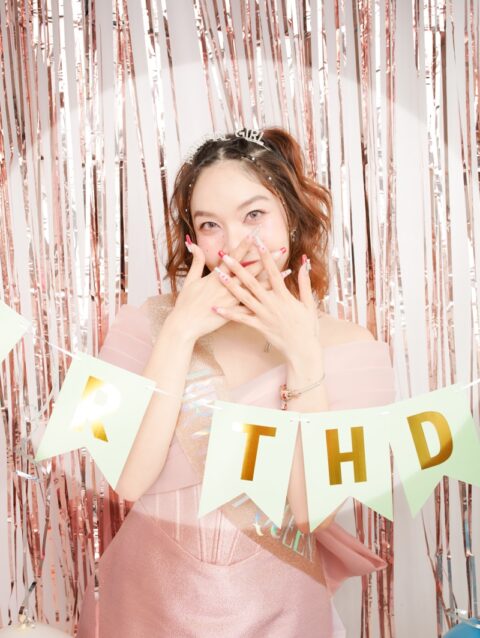 A woman in a pink dress standing in front of a photo booth