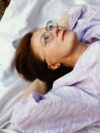 A woman with glasses laying on a blanket