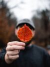 A man holding up a leaf in front of his face
