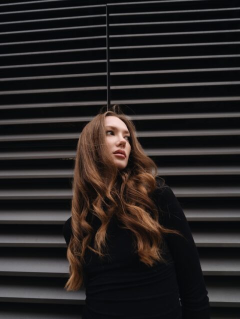 A woman with long hair standing in front of a wall