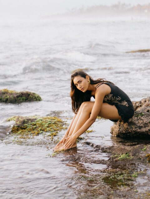 A woman sitting on a rock in the water