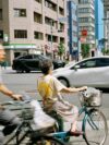 A couple of people riding bikes down a street
